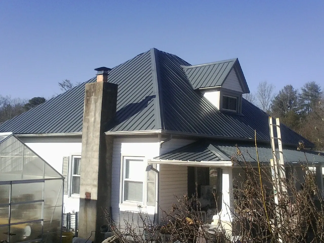 Dark blue standing seam metal roof on a white farmhouse with dormer — Slate & Tile Roof Repair by Roofing Brothers in Trail