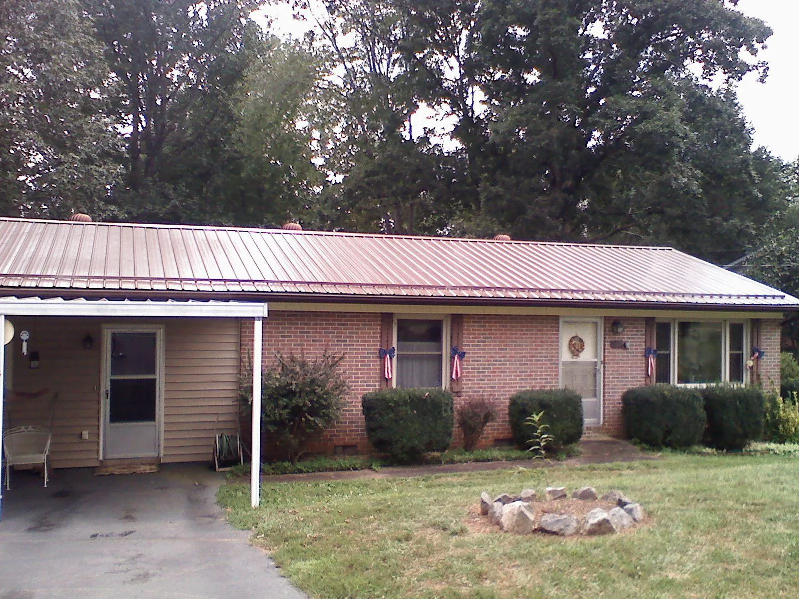 Bronze metal roof and carport on a brick ranch home — Roof Repair work by our crew in Trail
